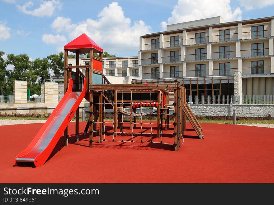 Playground with red slider in a front of modern building. Playground with red slider in a front of modern building