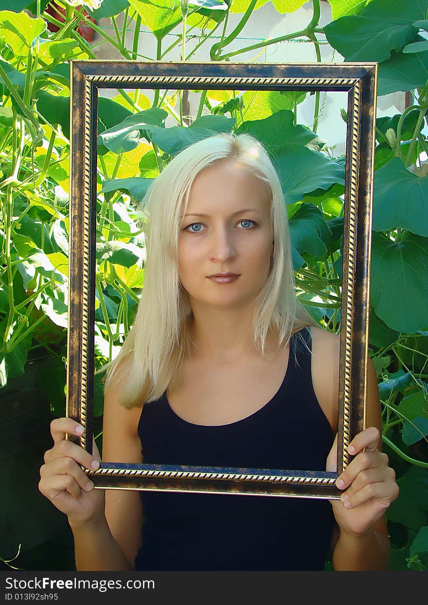 Young beautiful woman with frame in a summer garden. Young beautiful woman with frame in a summer garden.