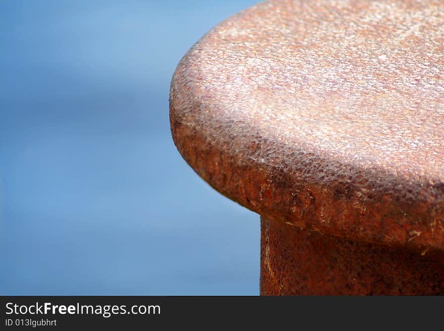 Rusty bollard,closeup, in front of a water background