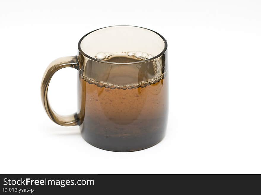 A transparent black cup with tea and tealeafs