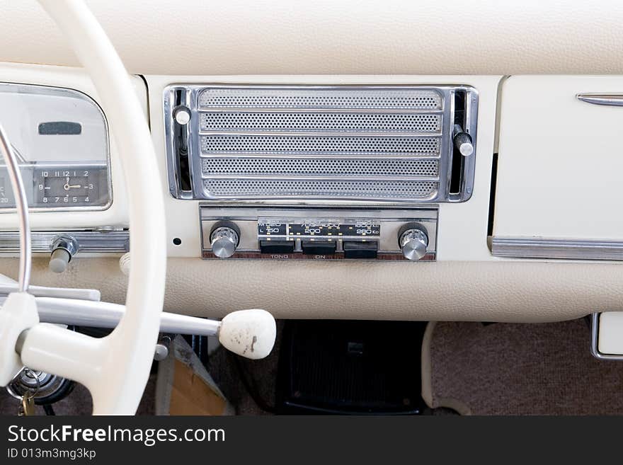 Old style steering wheel and white dashboard. It can also be seen the gear lever on th esteering column, the old stereo and the speaker. Old style steering wheel and white dashboard. It can also be seen the gear lever on th esteering column, the old stereo and the speaker.