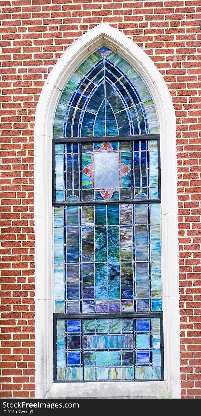 A beautiful stained glass window in a brick wall of a church