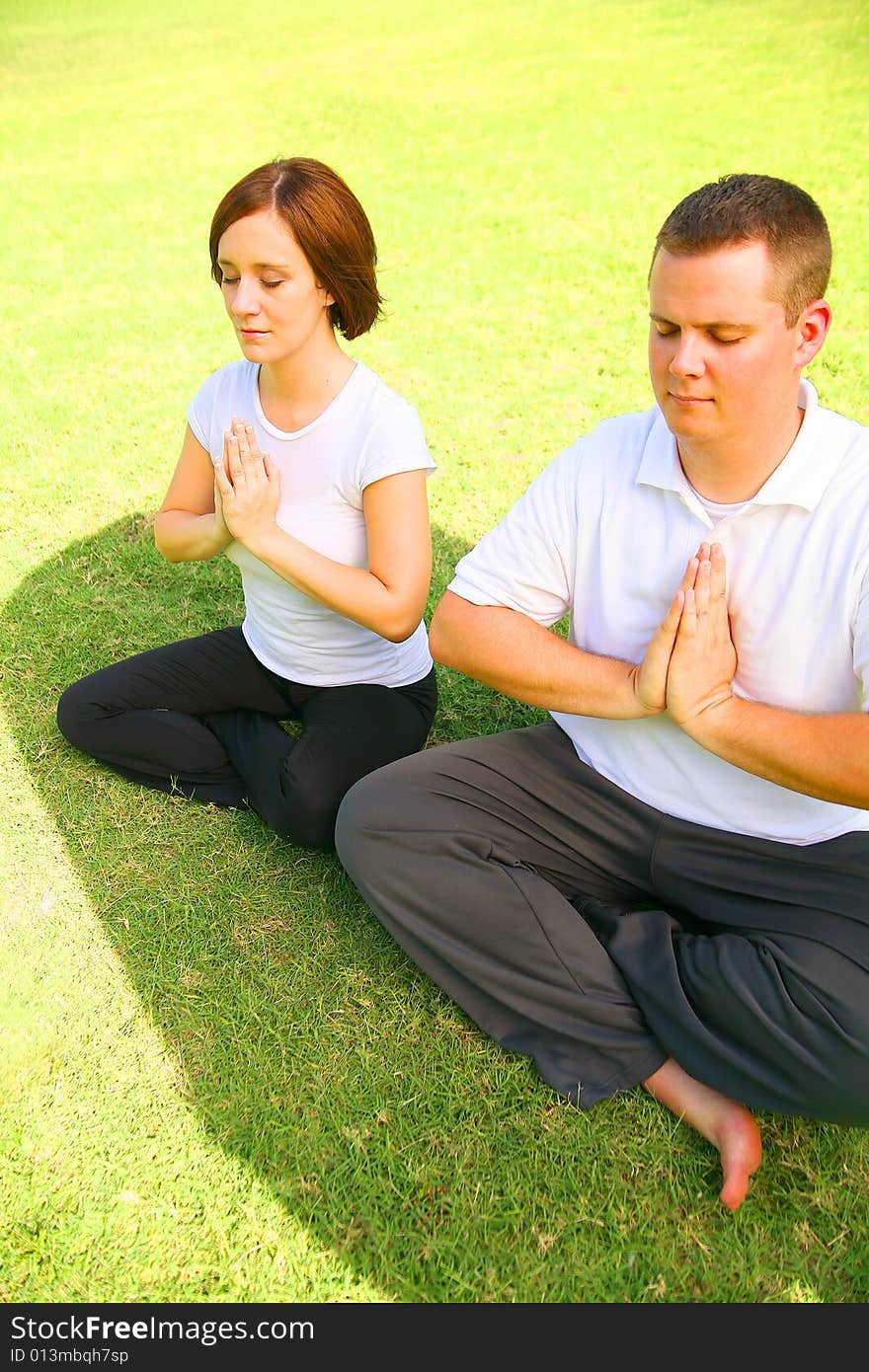 Young caucasian couple meditate outdoor in a park. concept for yoga, family activity or wellbeing. Young caucasian couple meditate outdoor in a park. concept for yoga, family activity or wellbeing