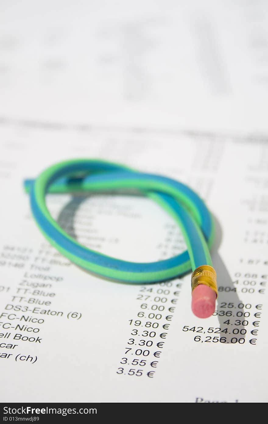 A green and blue striped rubber pencil tied in knot sitting on accounting printout. A green and blue striped rubber pencil tied in knot sitting on accounting printout