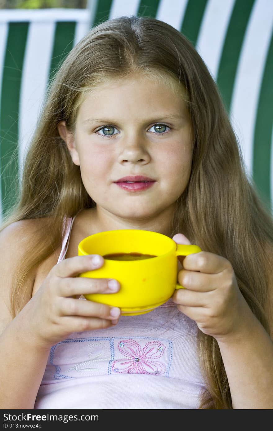 Little blond girl with yellow cup of tea in her hands. Little blond girl with yellow cup of tea in her hands