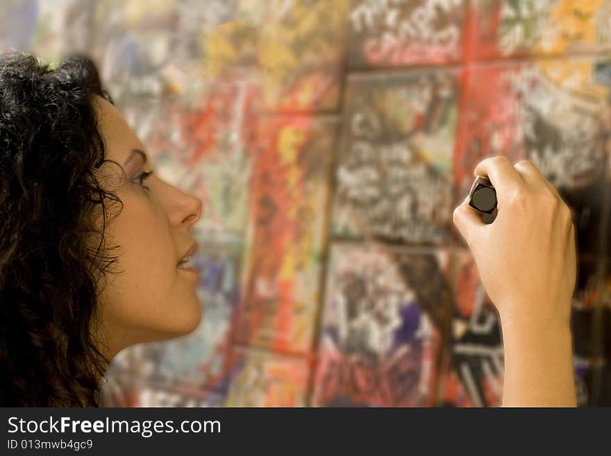 Woman painting something on a brick wall. Woman painting something on a brick wall