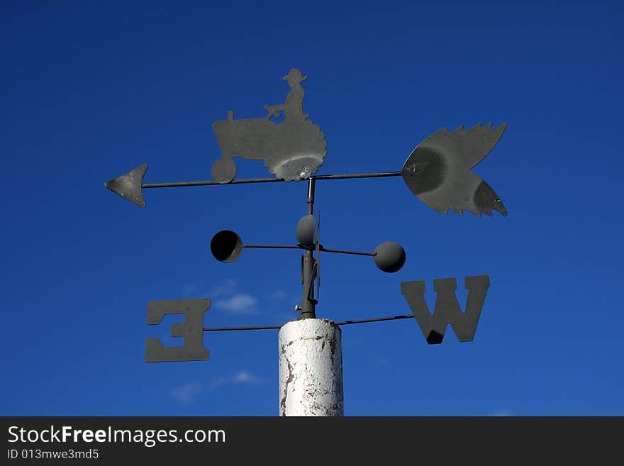 Old wind vane against clear blue sky