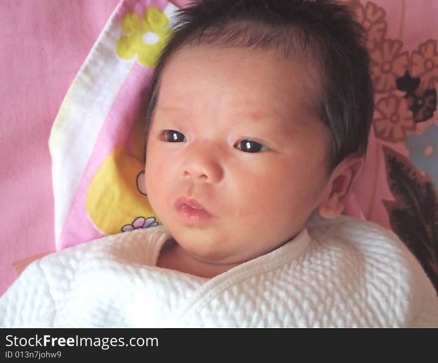 Lovely baby in white on a bed