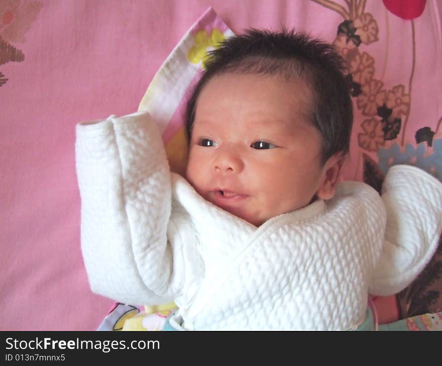 Lovely baby in white on a bed