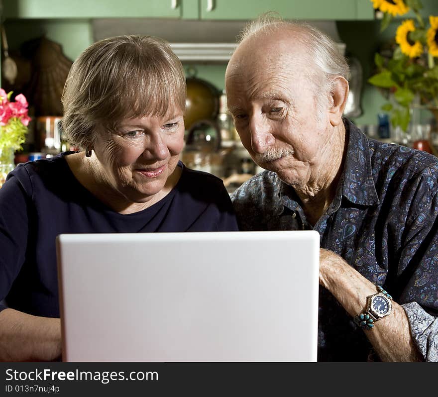 Senior Couple in their Dining Room with a Laptop Computer. Senior Couple in their Dining Room with a Laptop Computer