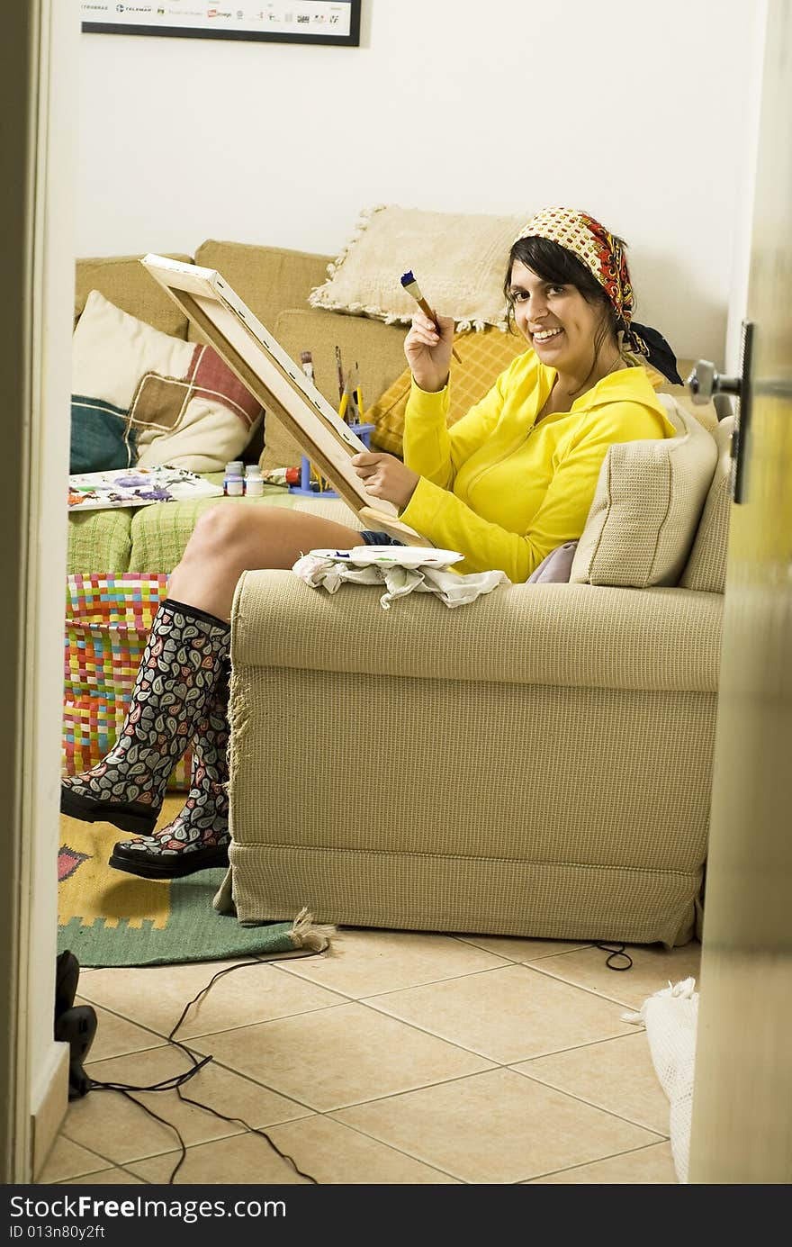 Artist painting on her couch. Vertically framed photo.