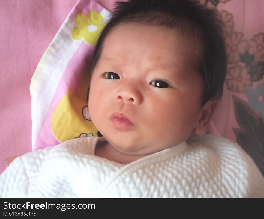 Lovely baby in white on a bed