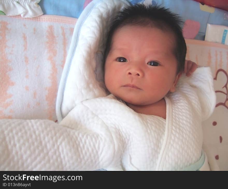 A Chinese baby is waving her hand on a bed. A Chinese baby is waving her hand on a bed