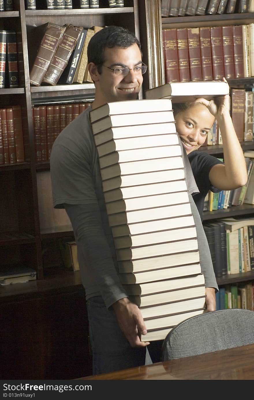 Students playing around in office stacking books. Vertically framed photo. Students playing around in office stacking books. Vertically framed photo.