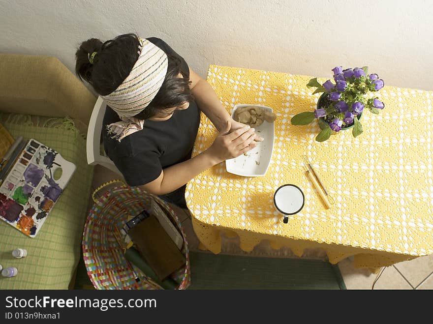 Top view of artist sitting at table molding clay. Horizontally framed photo. Top view of artist sitting at table molding clay. Horizontally framed photo.