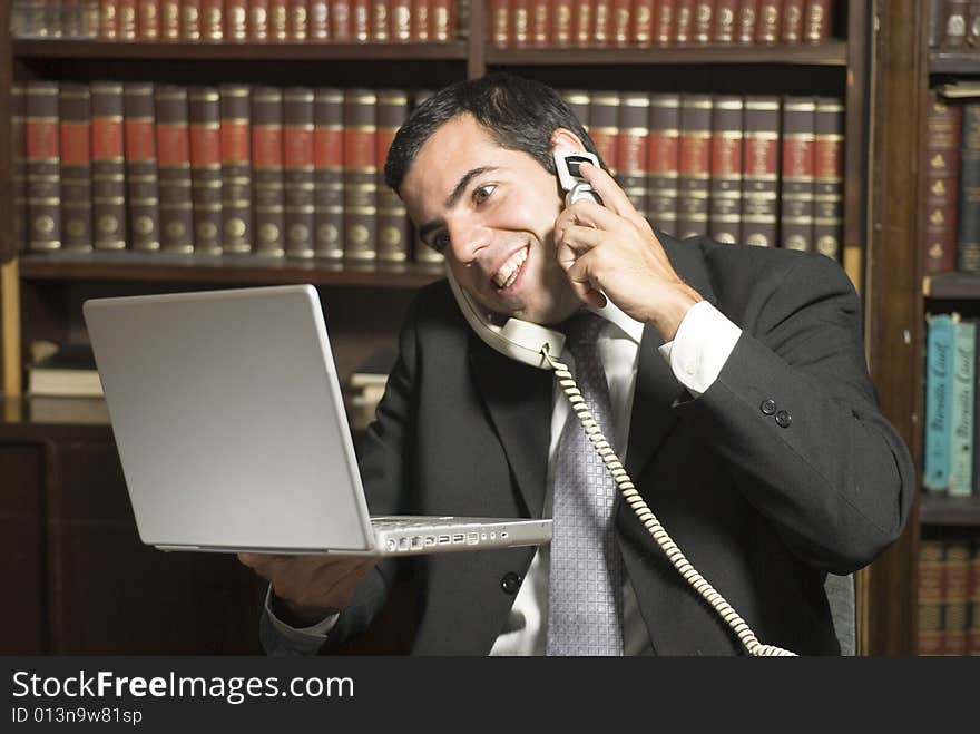 Businessman on cell phone in office holding computer. Horizontally framed photo. Businessman on cell phone in office holding computer. Horizontally framed photo.