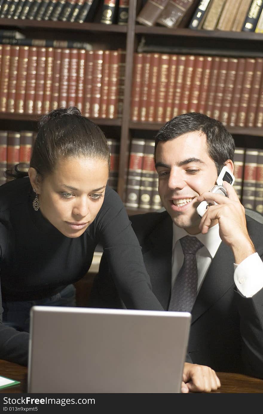 Businessman and woman looking at laptop and talking on phone. Vertically framed photo. Businessman and woman looking at laptop and talking on phone. Vertically framed photo.