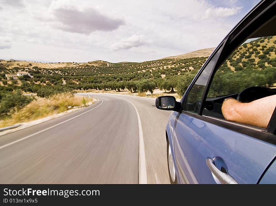 Cruising the countryside in a blue car at high speed.