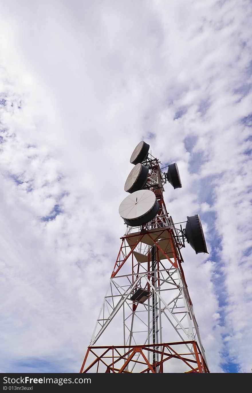 Telecommunication antenna under clouded sky.