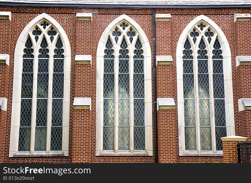 Three stained glass windows in brick wall of church