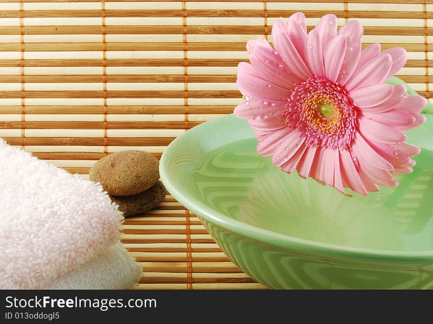 Composition with a beautiful pink flower, spa stone green bowl and towels