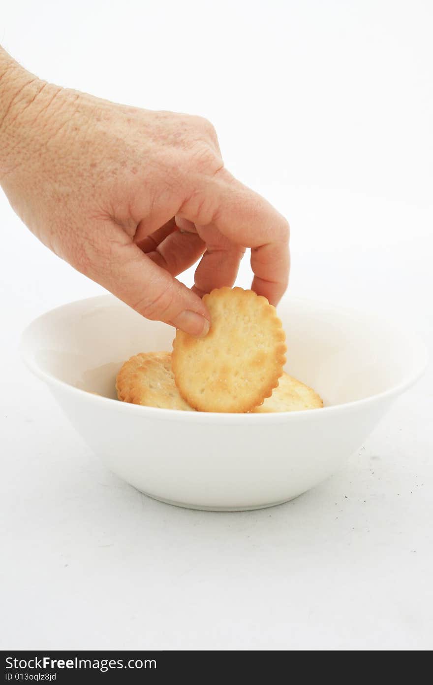 A white caucasian hand reaching into a white bowl taking a snack isolated on a white background. A white caucasian hand reaching into a white bowl taking a snack isolated on a white background.