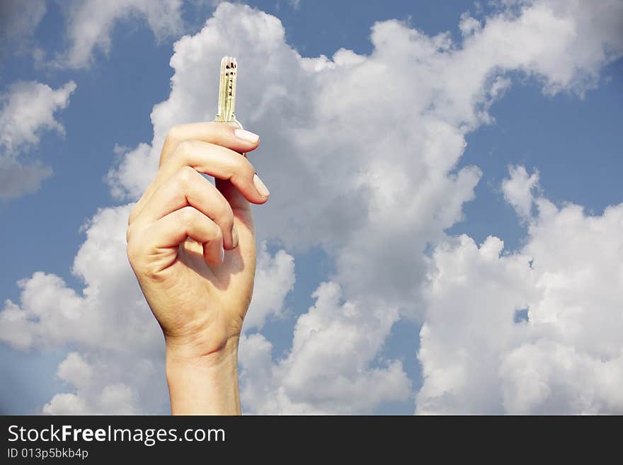 Hand holding a key in the air with the sky as a background. Hand holding a key in the air with the sky as a background