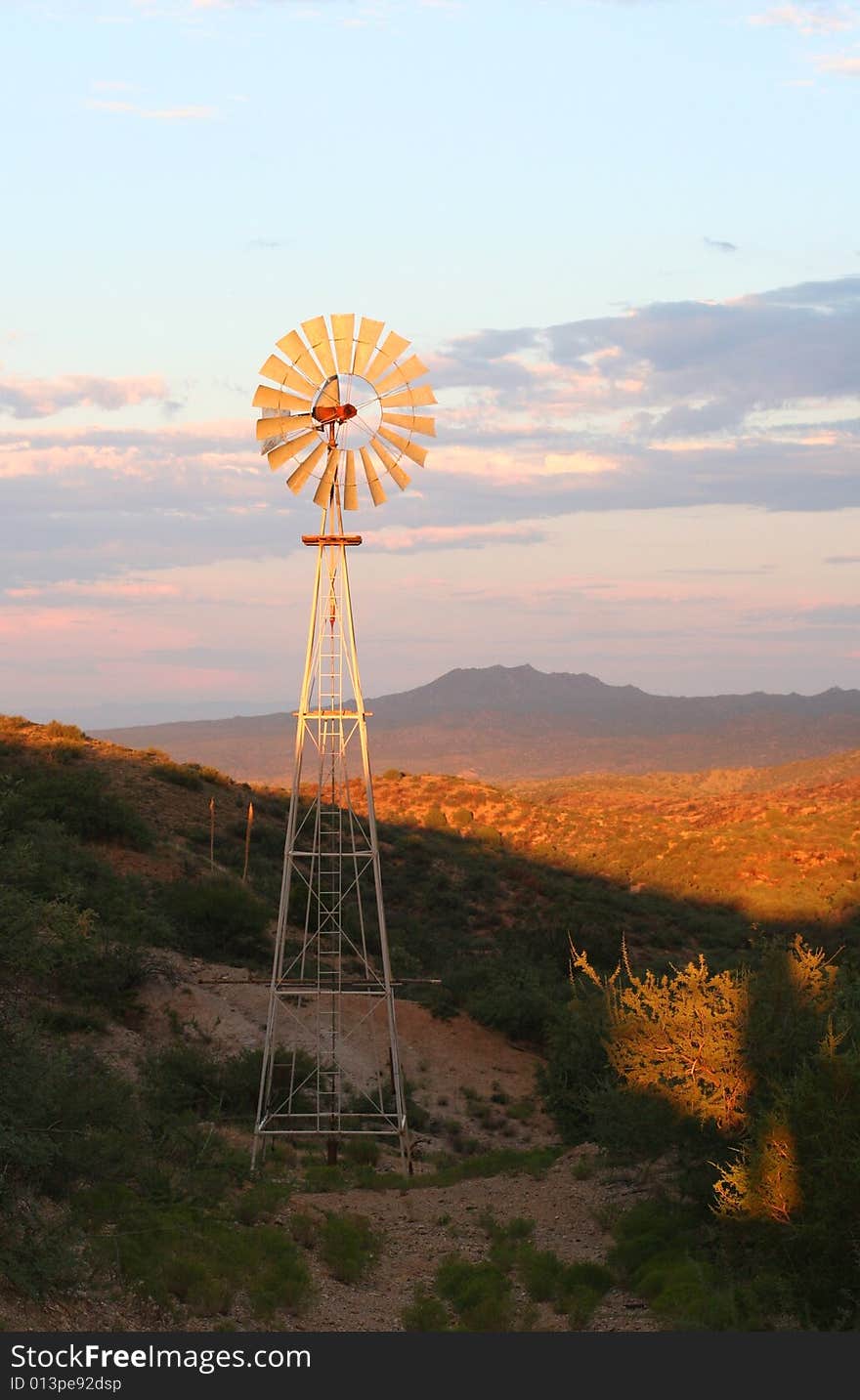 Water pumping windmill lit up at sunset in the Arizona desert. Water pumping windmill lit up at sunset in the Arizona desert