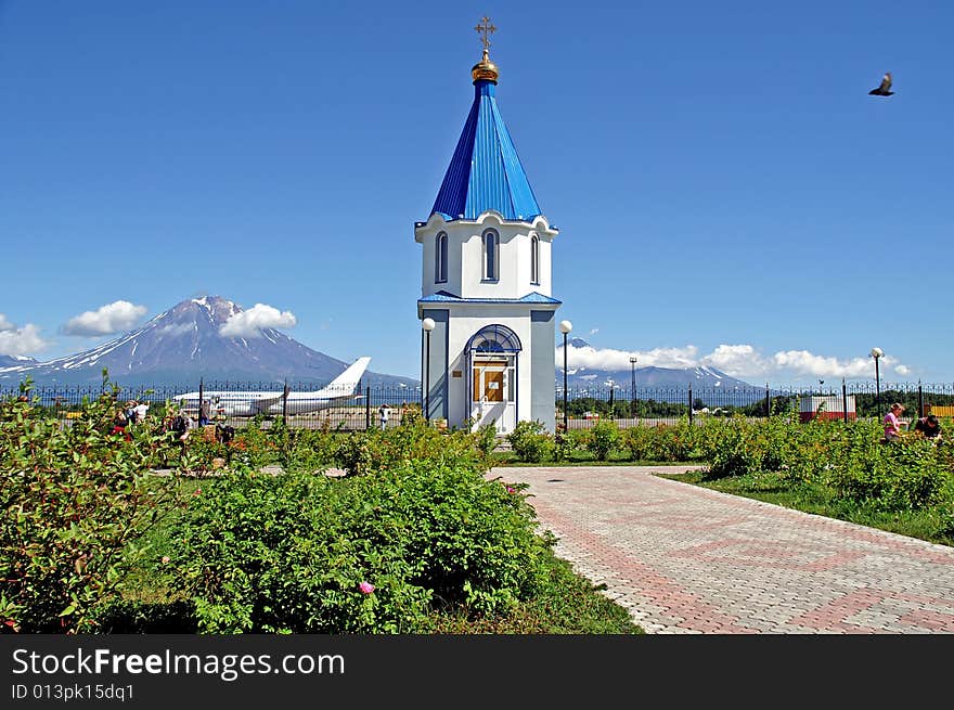 The Chapel with cross in aeroport on background vulcan and plane.