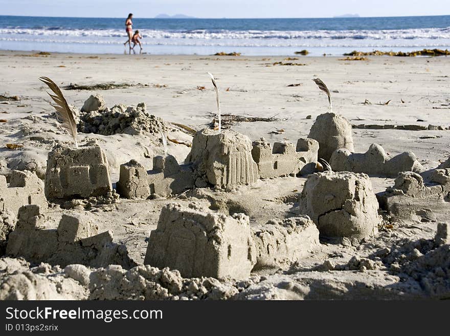 Sand castle on the ocean coast, chldren running on the background