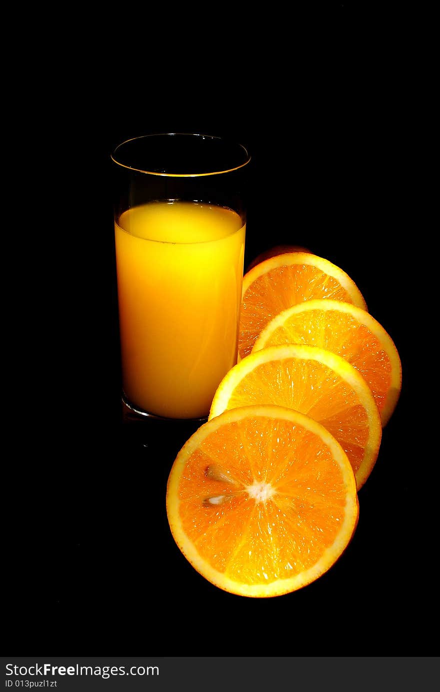 Glass of juice, oranges on black backgound. Glass of juice, oranges on black backgound