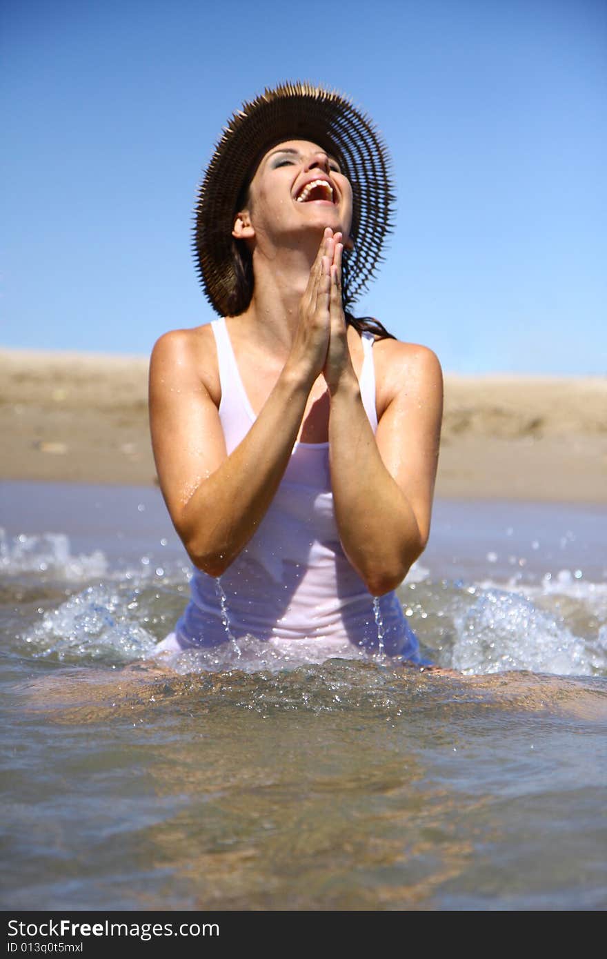 Woman praying in ocean with waves and hat