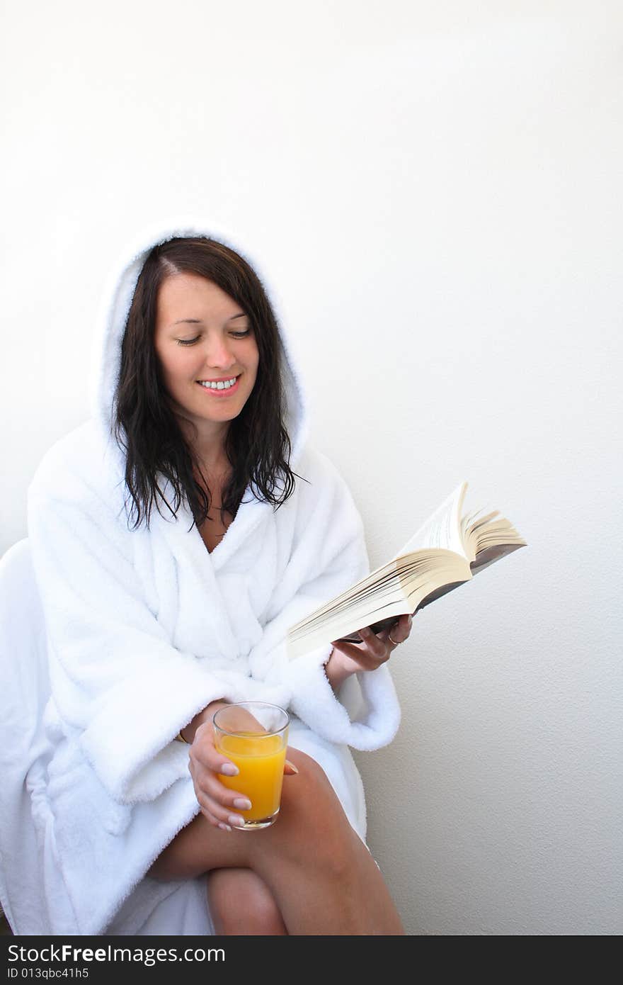 Young smiling woman with orange juice reads book. Young smiling woman with orange juice reads book