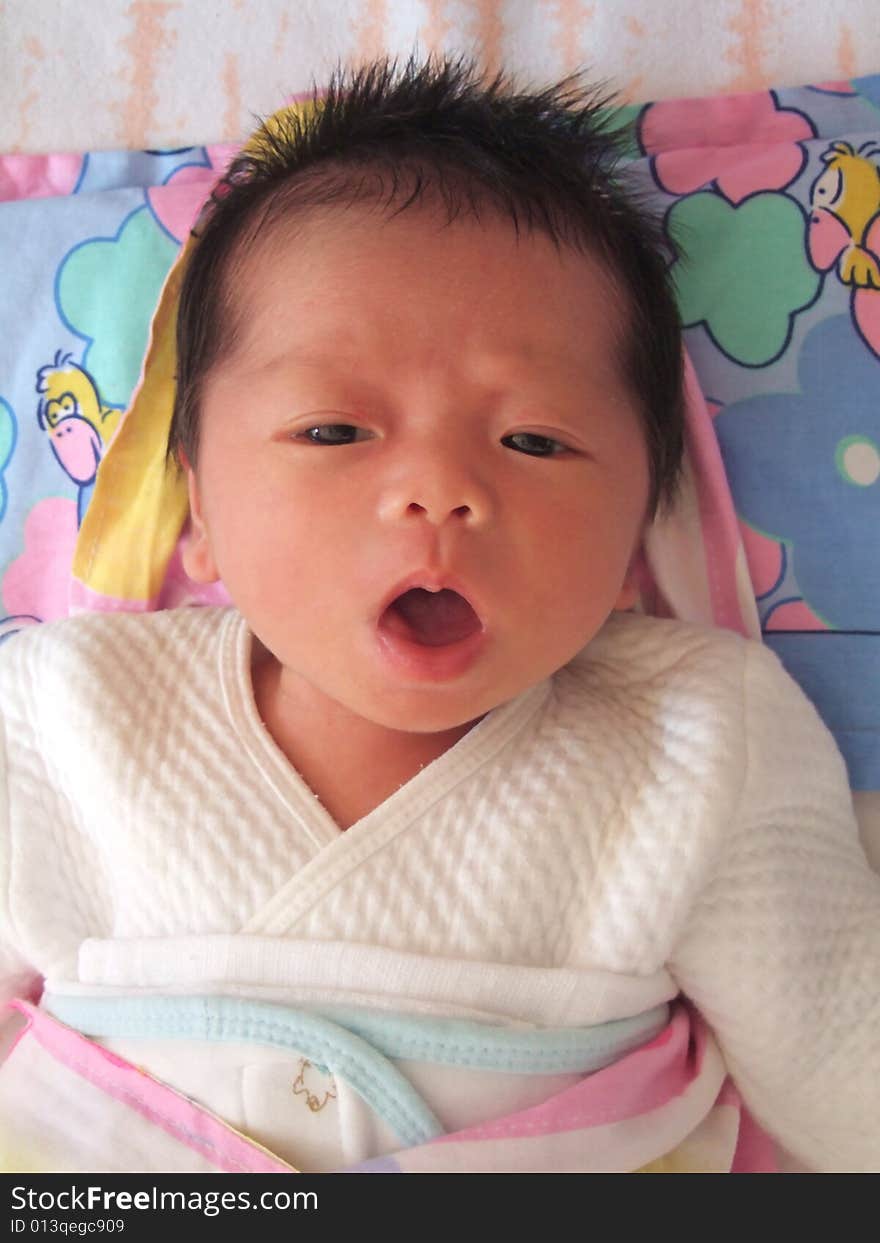 A Chinese baby on a bed, opening her mouth. A Chinese baby on a bed, opening her mouth