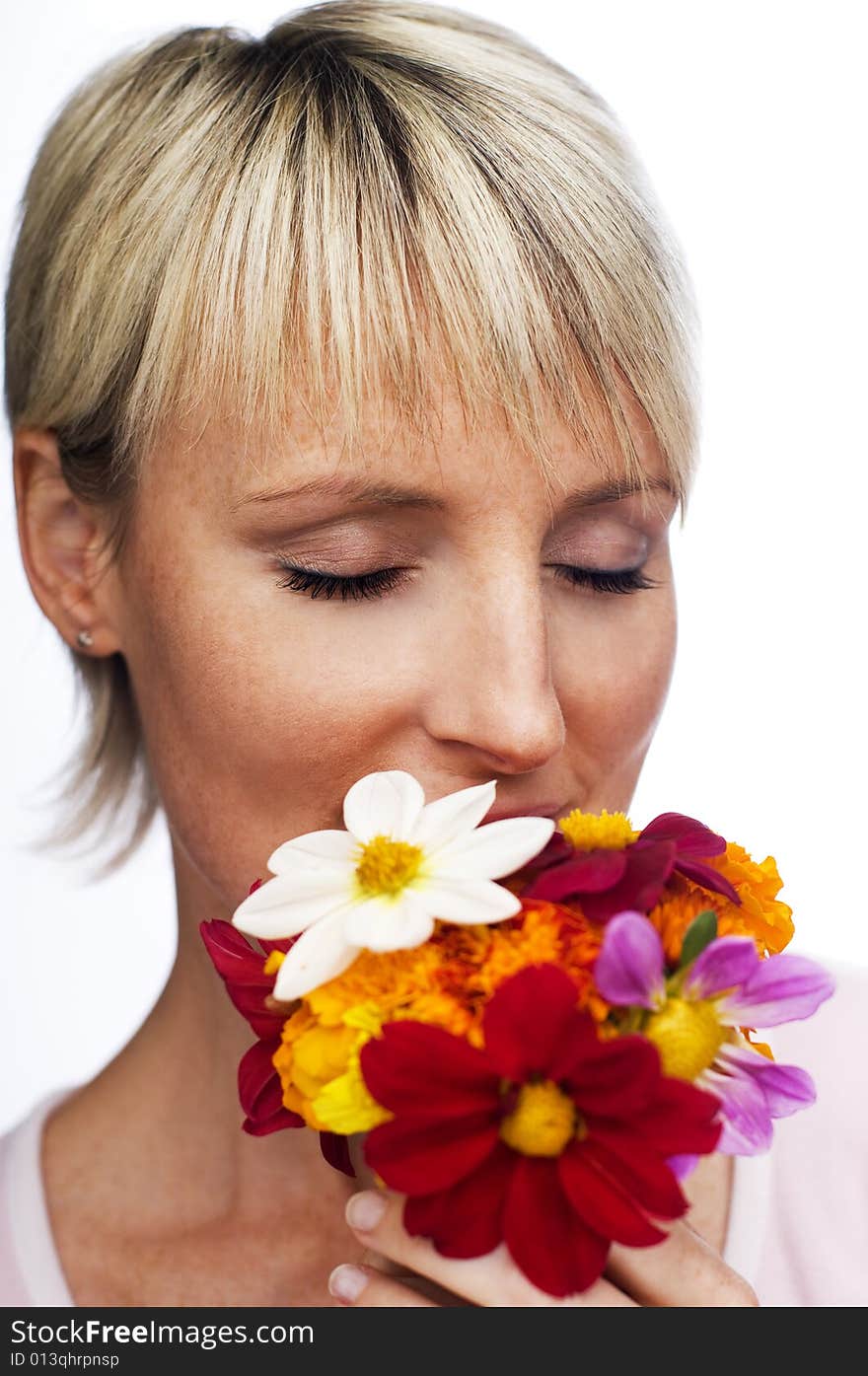 Young blond woman smelling flowers close up