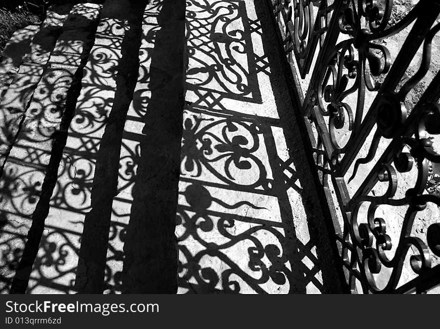 Patterned shade on steps from the forged gate