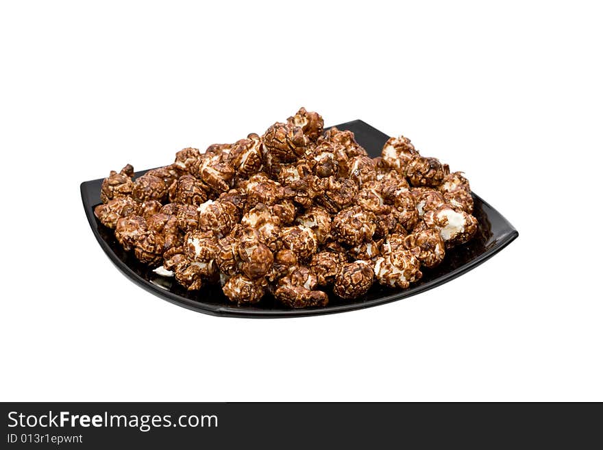 Chocolate popcorn on the black plate isolated on white