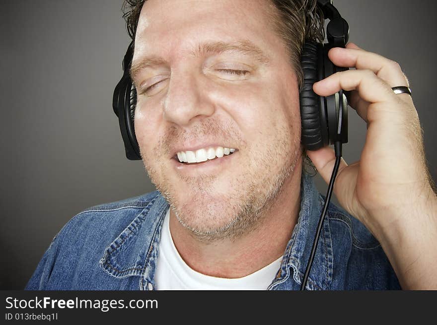 Man Wearing Headphones Enjoying His Music on a Grey Background.