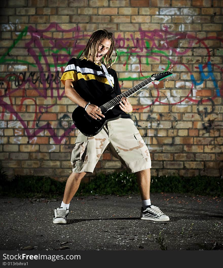 Young man with guitar against the wall. Young man with guitar against the wall.