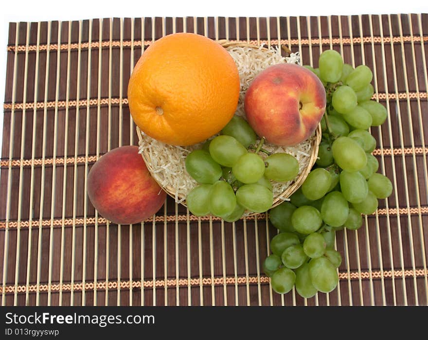 Orange and grapes in a basket on a napkin