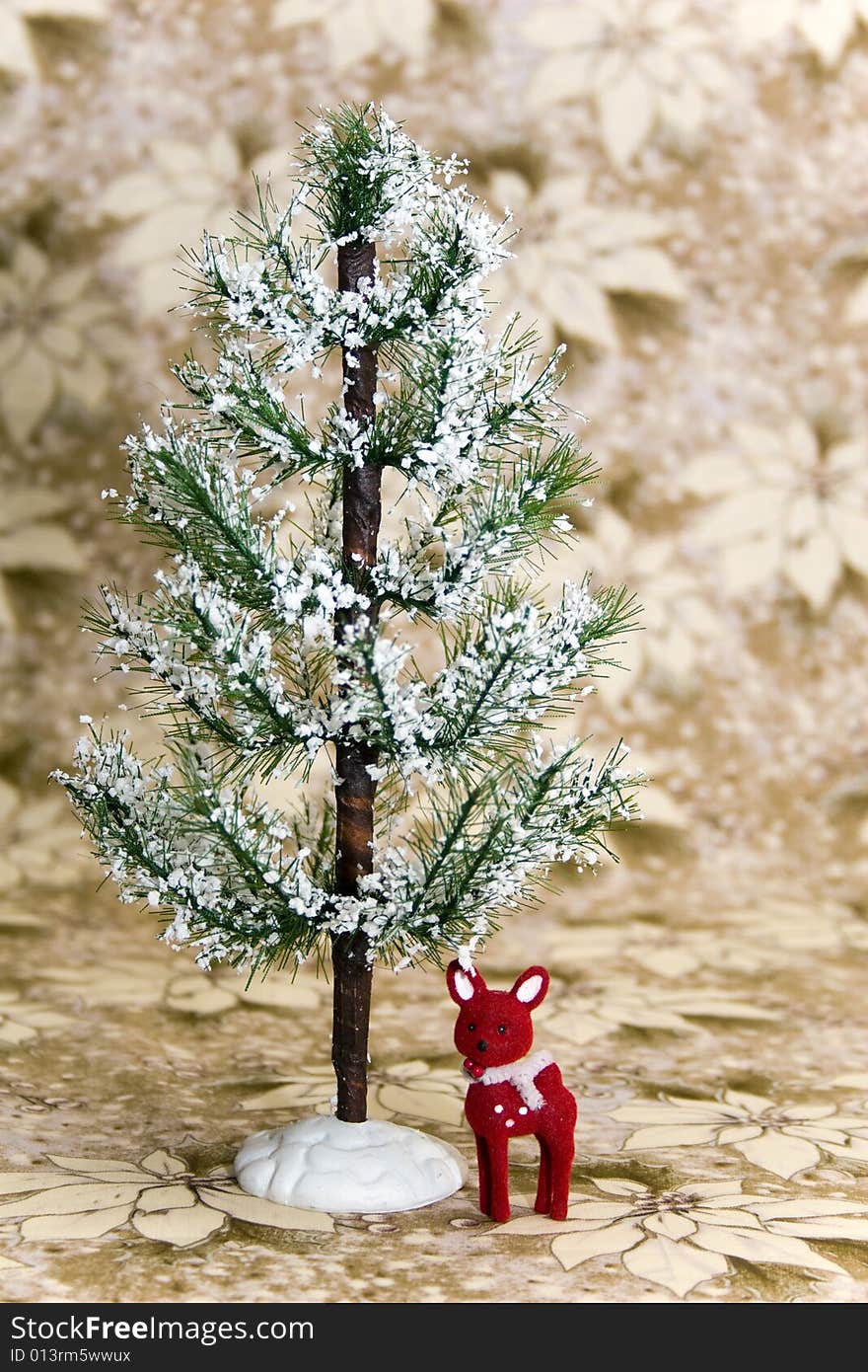 Red reindeer standing under an evergreen tree with snow. Background is white/gold poinsettia. Red reindeer standing under an evergreen tree with snow. Background is white/gold poinsettia.