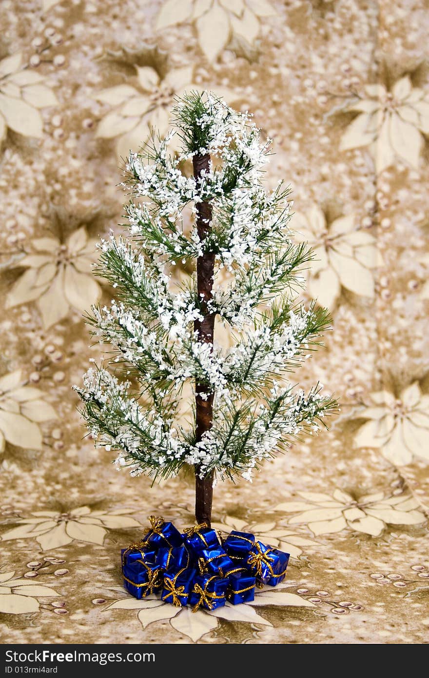 Evergreen tree with white snow, blue presents underneath, and against a background of white/gold poinsettia. Evergreen tree with white snow, blue presents underneath, and against a background of white/gold poinsettia.