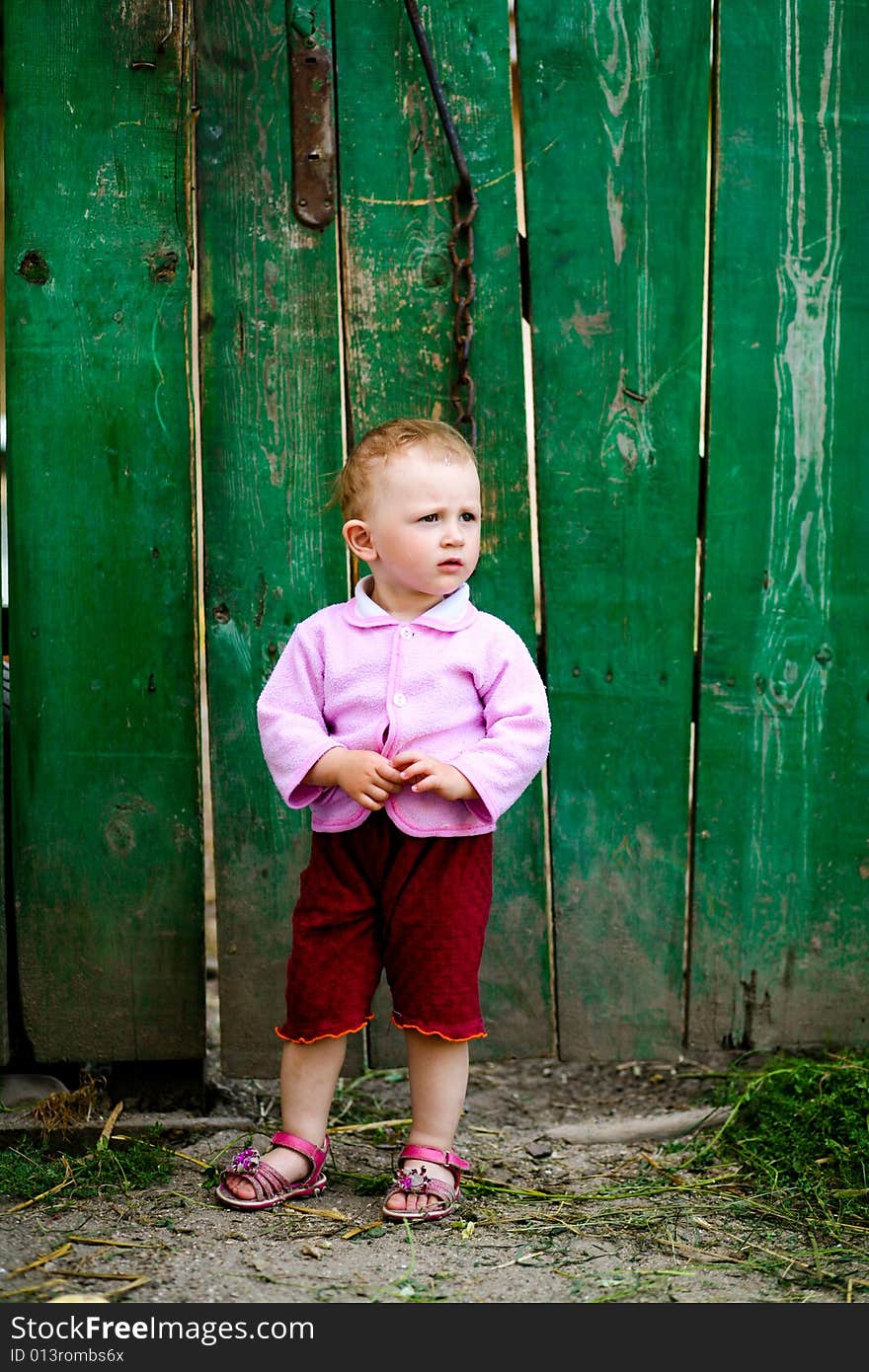 Baby-girl near green fence