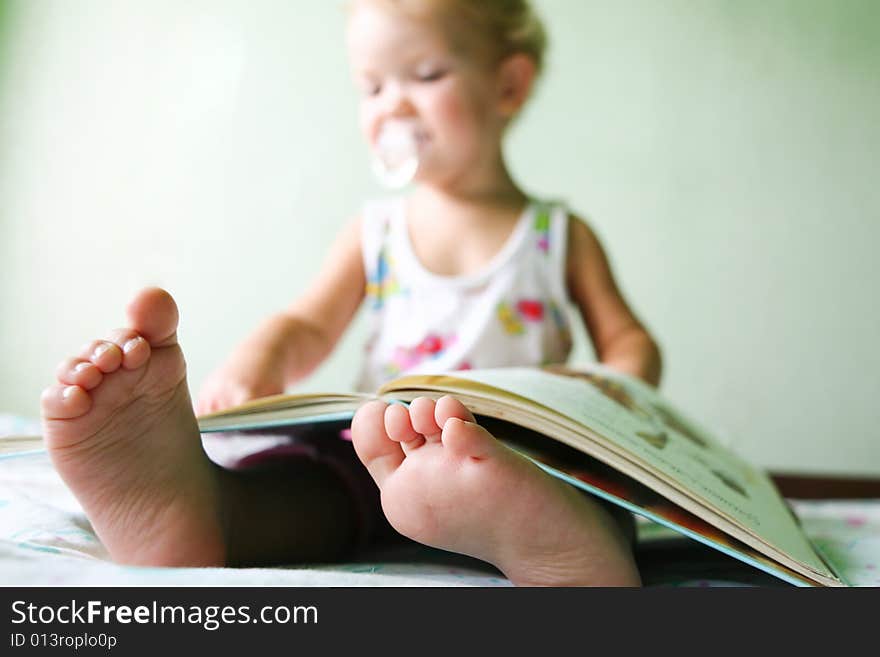 An image of a toddler reading a book. Foots closeup