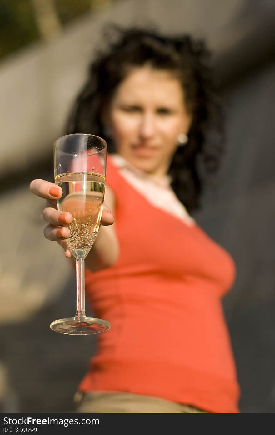 Outdoor portrait of woman with champagne glass, focus on glass