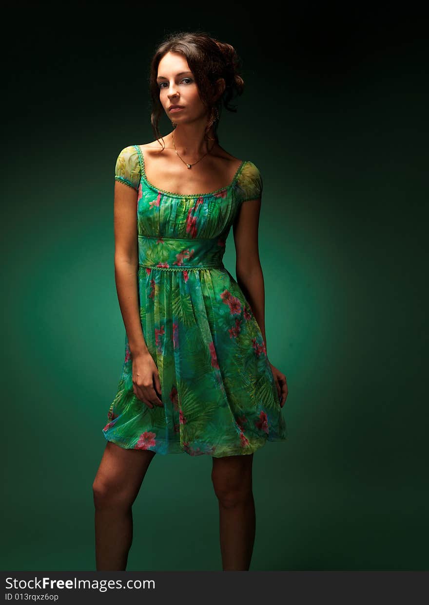 The beautiful girl on a green background in a green dress