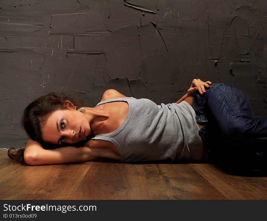 The young beautiful girl in a vest and jeans on a floor about an invoice wall