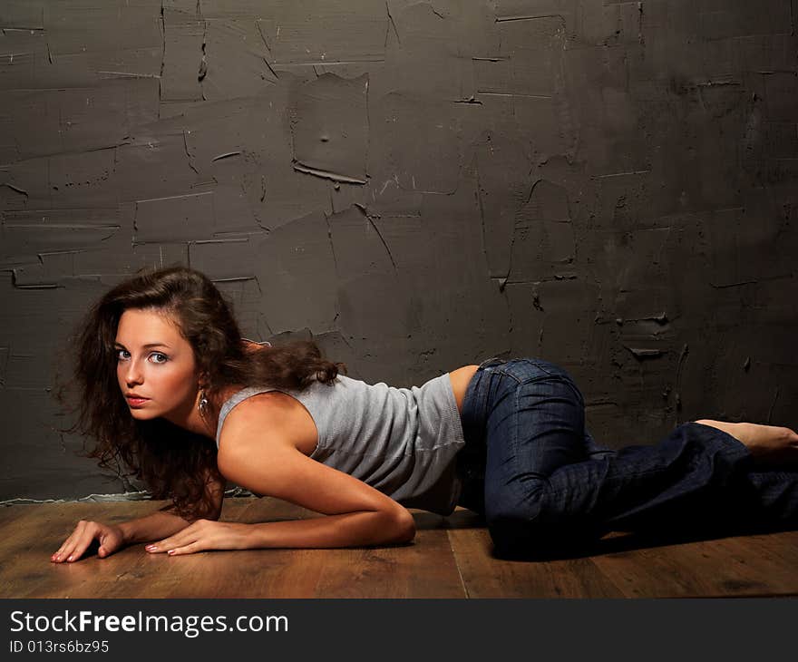 The young beautiful girl in a vest and jeans on a floor about an invoice wall