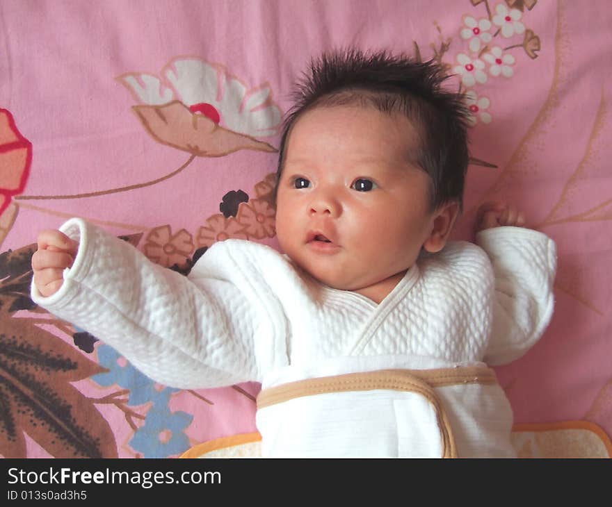 Lovely baby in white on a bed