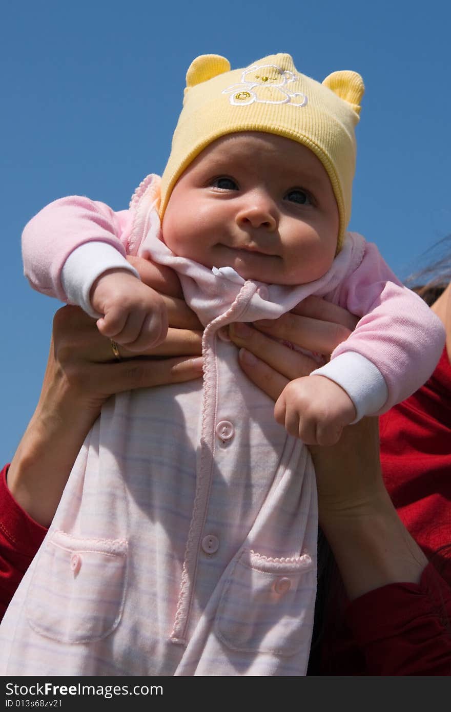 Little baby on mother's hands on blue sky background